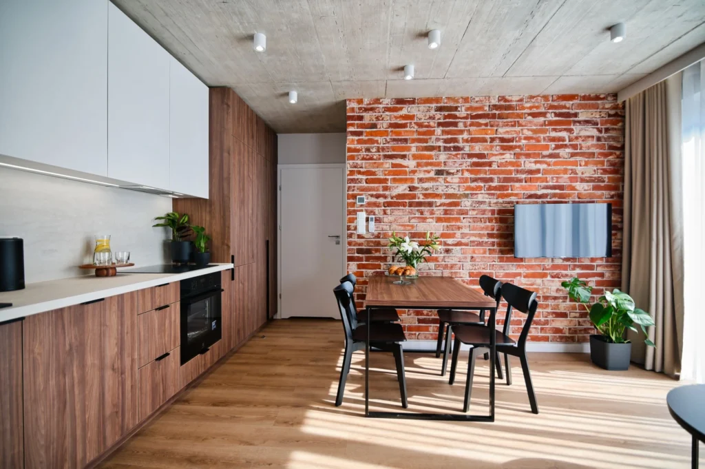 apartament w Zatorze – kuchnia z ceglaną ścianą, stołem i krzesłami
